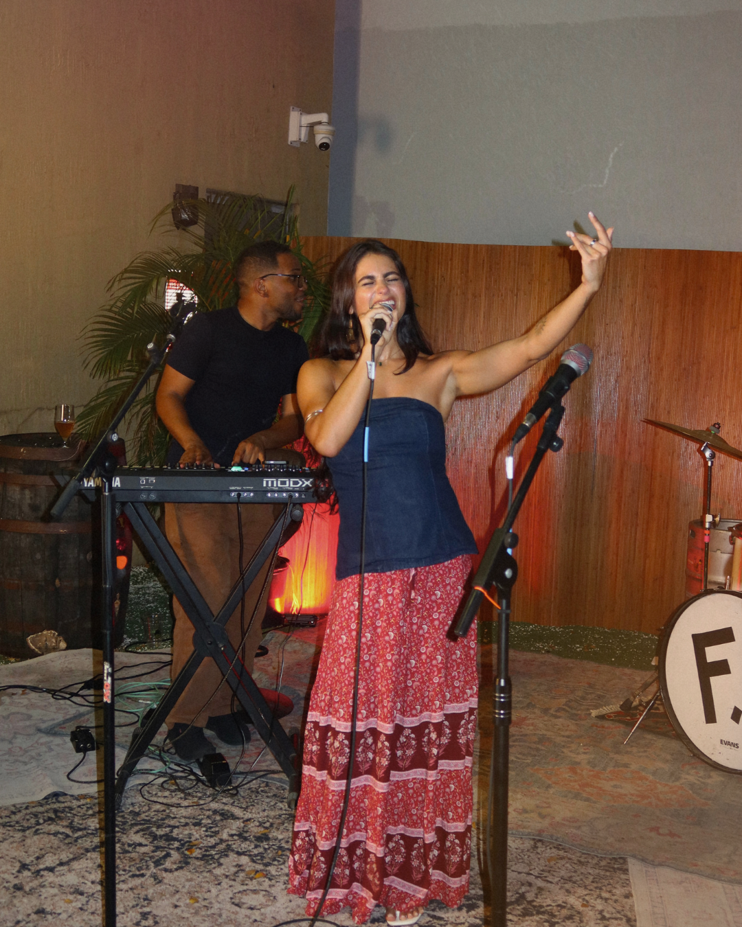 Paola Camila singing on stage with a keyboard player
